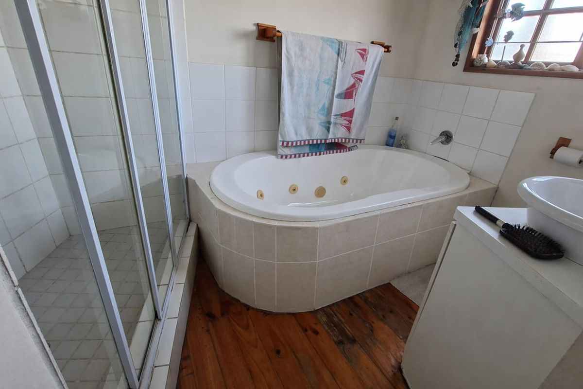 Bathroom featuring a built-in spa bath, separate shower enclosure, and a vessel sink with timber flooring.