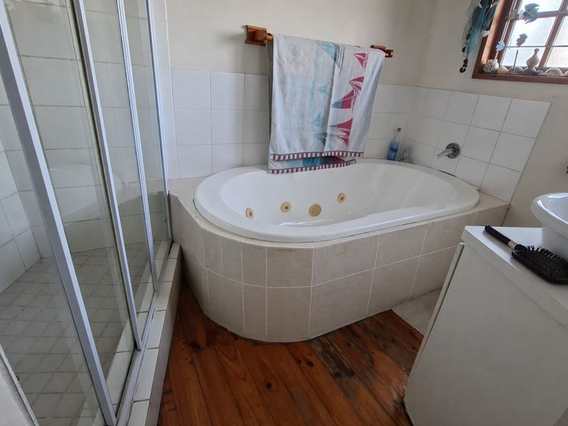 Bathroom featuring a built-in spa bath, separate shower enclosure, and a vessel sink with timber flooring.