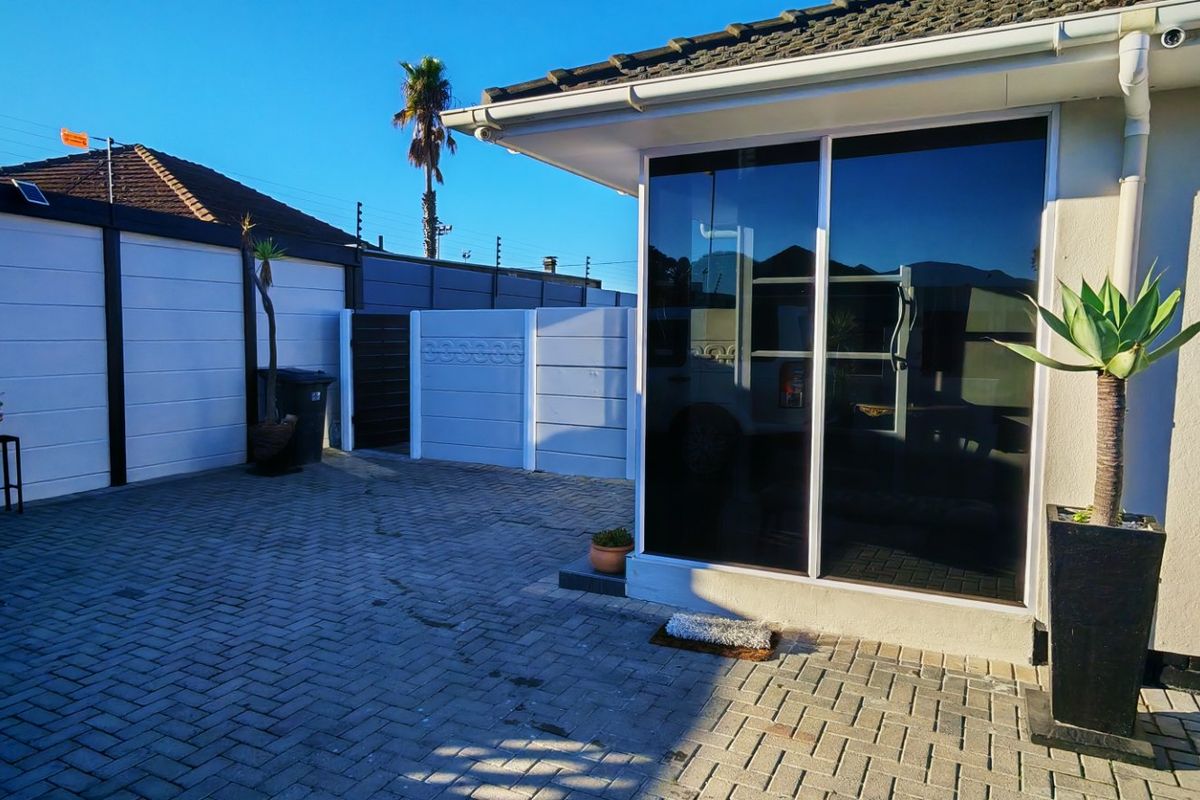 A paved rear courtyard area featuring a sliding glass door entrance and secure perimeter walling.