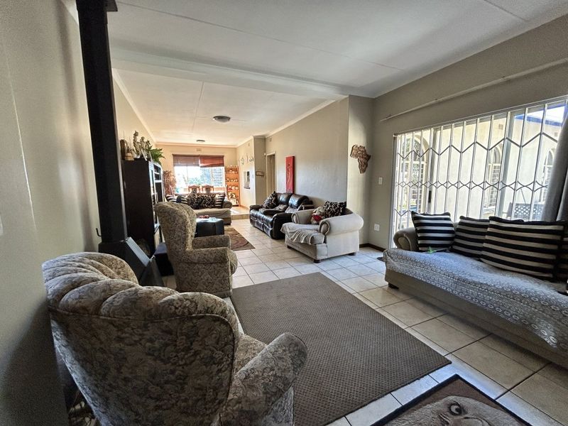 Spacious open-plan living area featuring tiled flooring, a freestanding fireplace, and large sliding doors with security gates leading to the exterior.