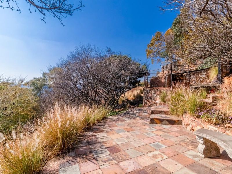 A landscaped garden area featuring stone-paved pathways, tiered stone retaining walls, and rustic stone steps leading to an elevated outdoor space.