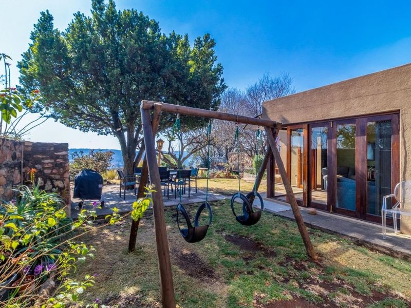 Rear garden area featuring a paved patio, established trees, and timber-framed glass sliding doors providing access to the interior living space.