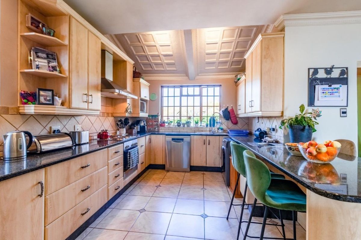 A well-maintained kitchen featuring light wood cabinetry, granite countertops, stainless steel appliances, and a distinctive coffered ceiling with tiled flooring.