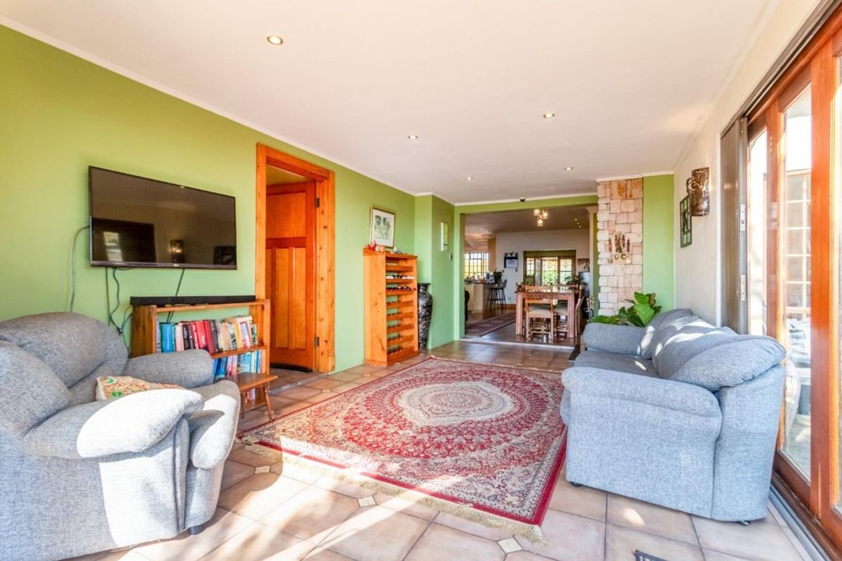 A spacious living room featuring tiled flooring, recessed lighting, and a stone-clad pillar, with direct access to the outdoor area through sliding glass doors.