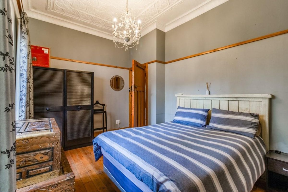 A well-maintained bedroom featuring original timber flooring, ornate ceiling detailing, and classic picture rails, creating a warm and character-filled living space.