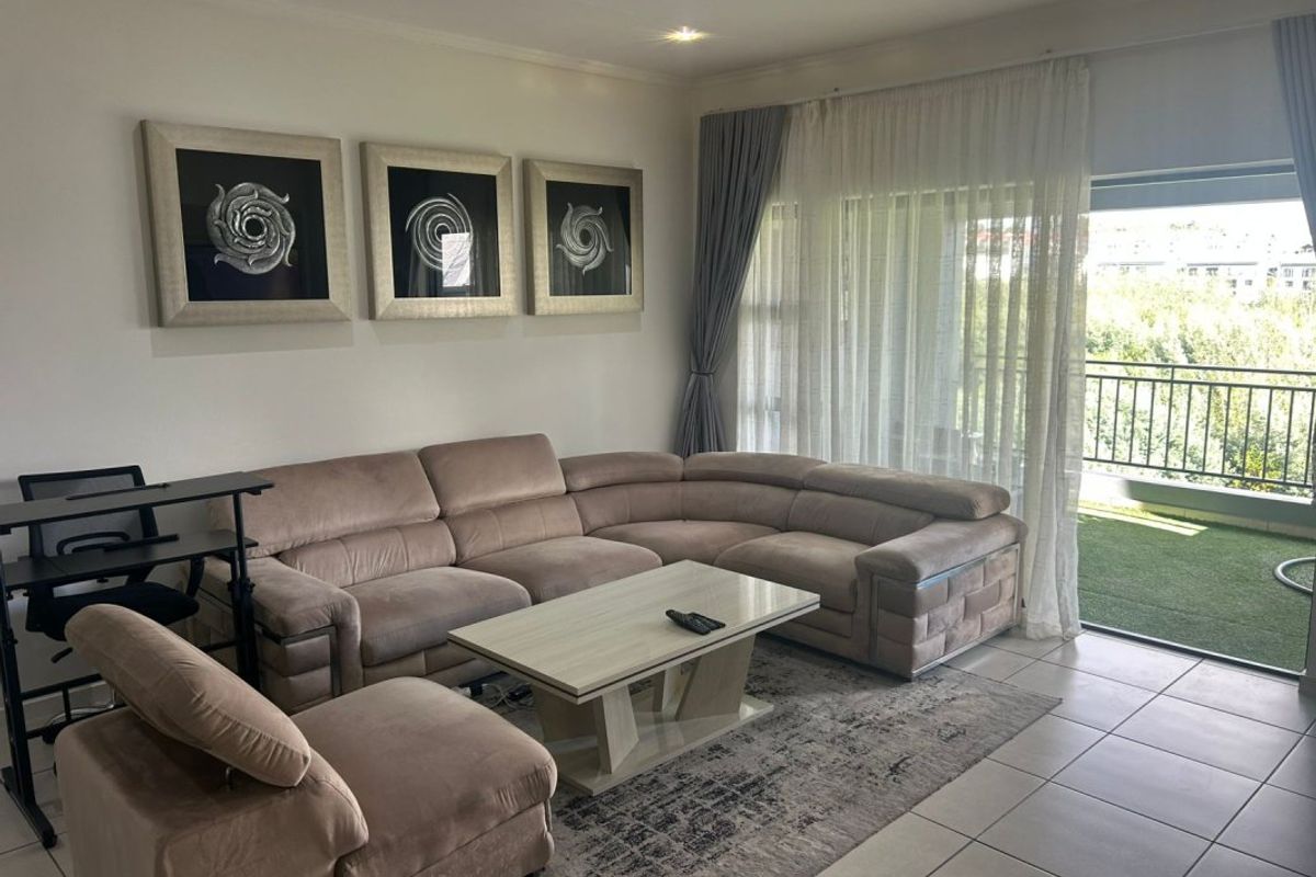 A well-lit living room featuring tiled flooring, recessed downlights, and a large sliding glass door providing direct access to an outdoor balcony area.