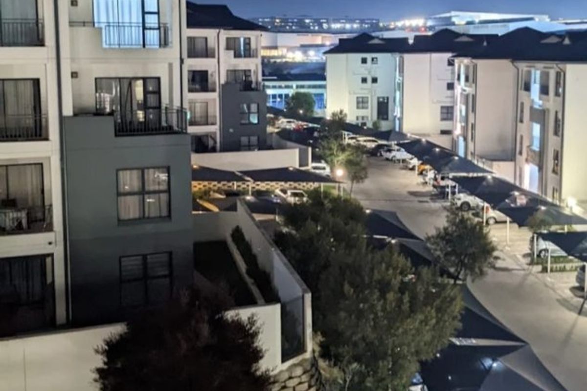 Night view of the apartment complex featuring multi-story residential buildings, covered parking structures, and landscaped grounds.