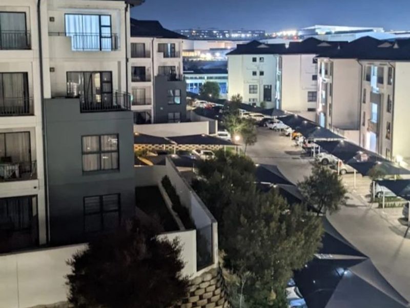Night view of the apartment complex featuring multi-story residential buildings, covered parking structures, and landscaped grounds.