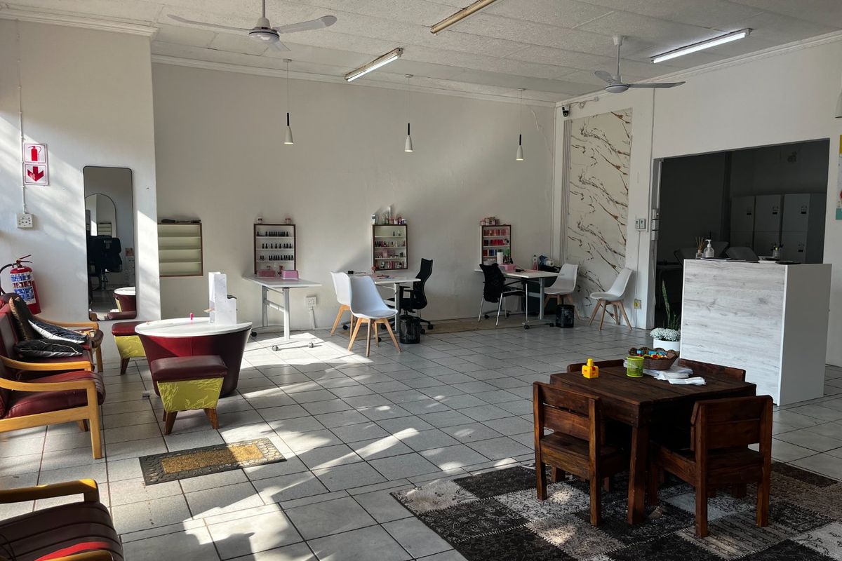 Open-plan commercial space featuring tiled flooring, ceiling fans, and a reception counter, suitable for a salon or retail environment.