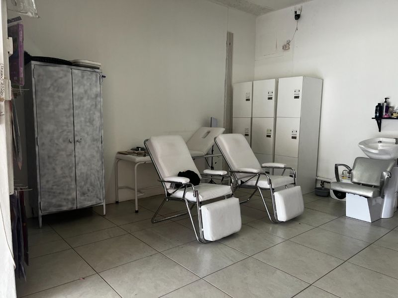 Commercial utility space featuring tiled flooring, built-in storage lockers, and a plumbed wash basin, suitable for salon or treatment room use.