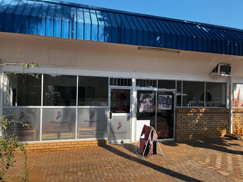 Front exterior view of a commercial storefront featuring large glass windows, a metal roof, and a paved entrance area.