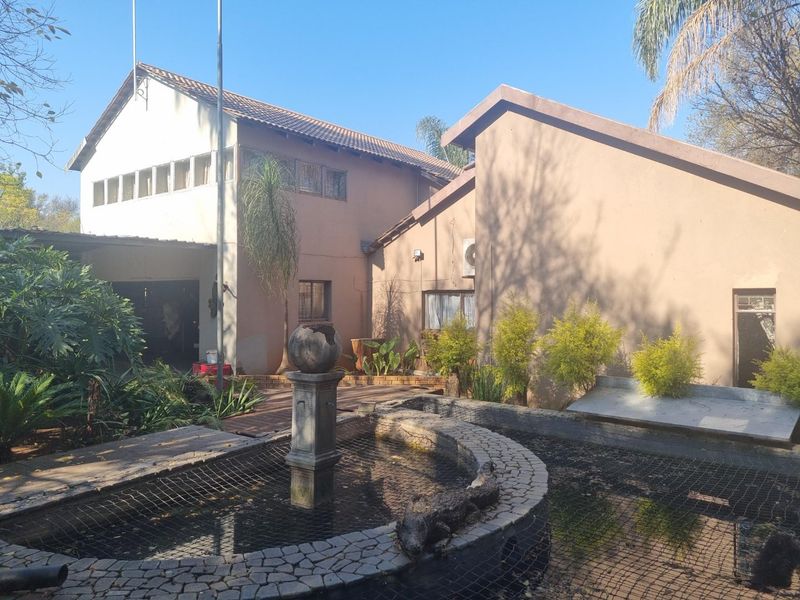 Rear exterior view of the house featuring a paved patio area, a decorative pond with a fountain, and established garden landscaping.