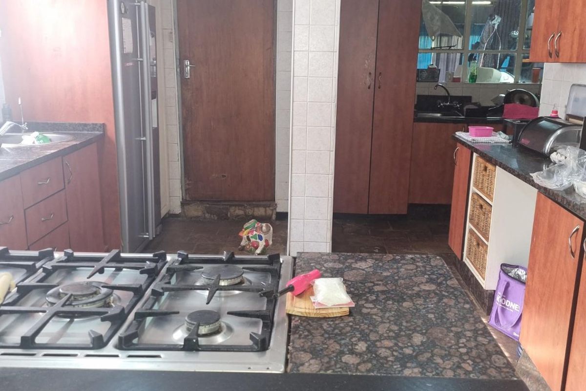 A functional kitchen featuring granite countertops, a gas cooktop, and ample built-in cabinetry, with visible signs of wear and ceiling water staining.
