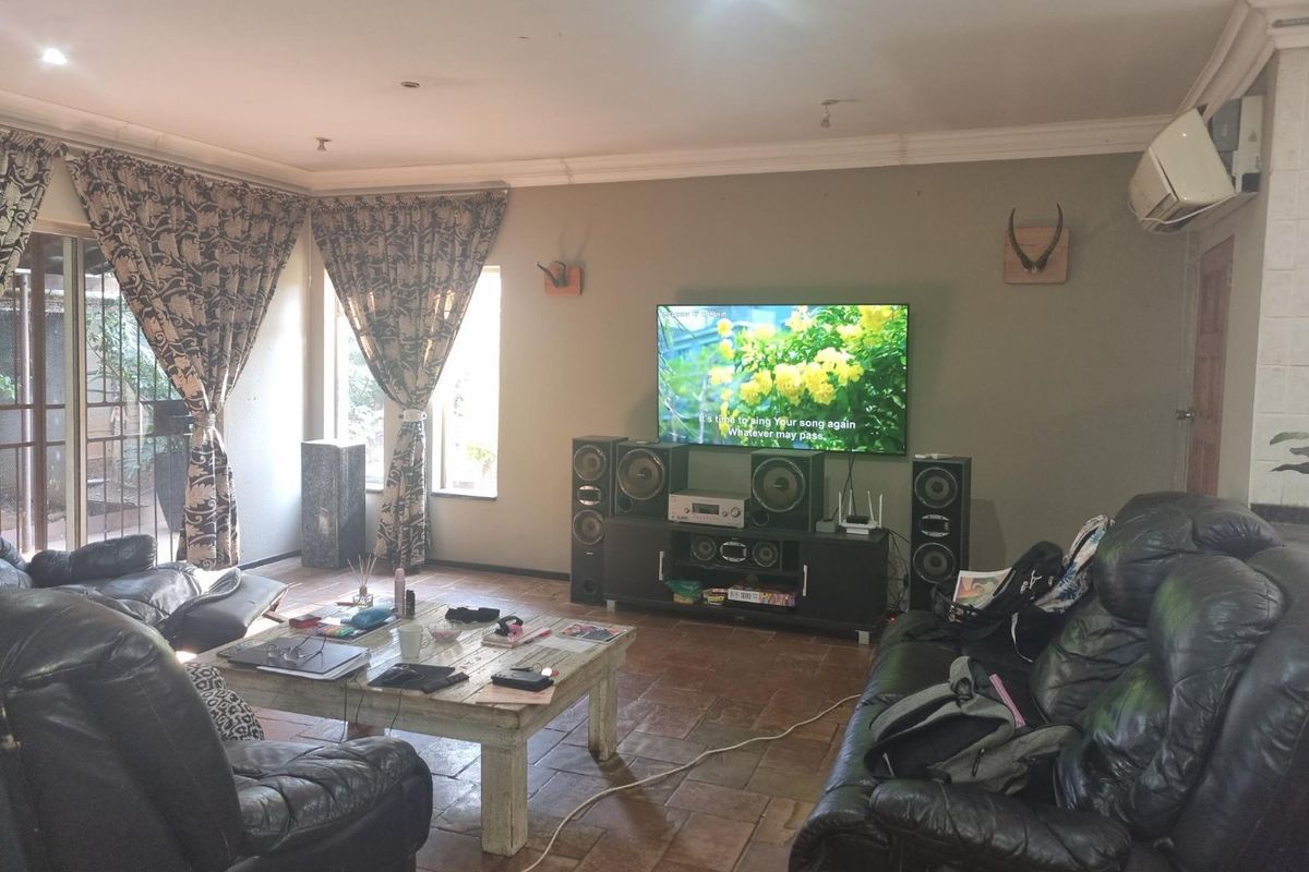 A comfortable living room featuring terracotta tile flooring, recessed lighting, and a wall-mounted air conditioning unit, with access to an outdoor area via sliding doors.