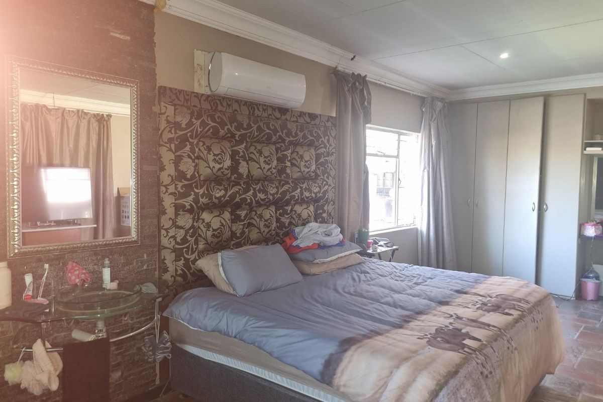 Bedroom featuring built-in cupboards, a wall-mounted air conditioning unit, and an integrated vanity basin area with tiled flooring.