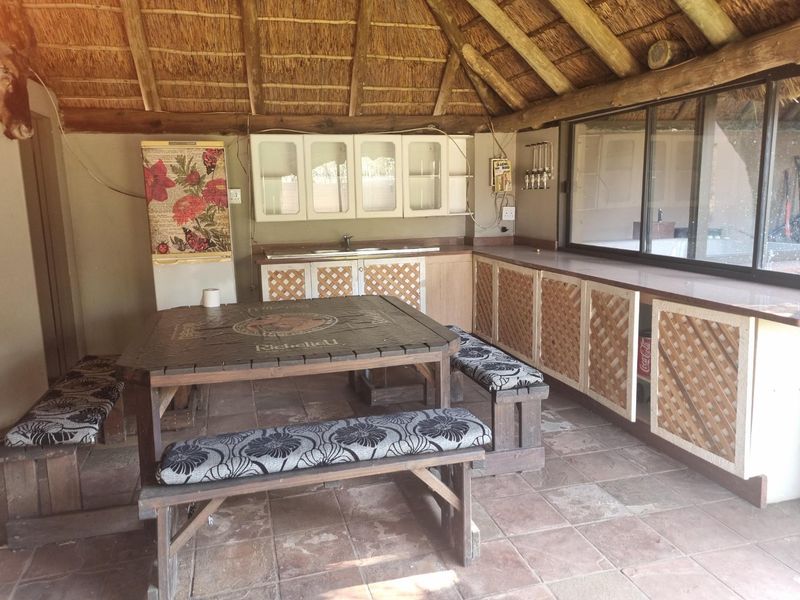 Covered outdoor entertainment area featuring a thatched roof, built-in cabinetry with sink, and tiled flooring, ideal for casual dining and hosting.