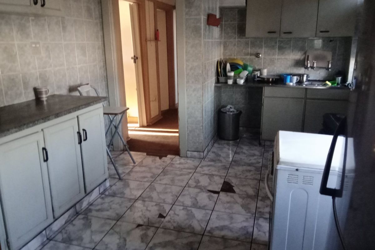 A dated kitchen featuring tiled flooring, wall tiles, and built-in cabinetry, requiring cosmetic updates to improve the overall aesthetic and functionality.