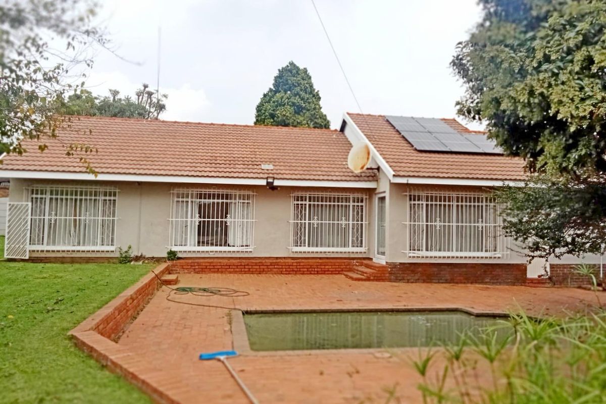 Rear view of the house featuring a swimming pool, brick patio area, and roof-mounted solar panels.
