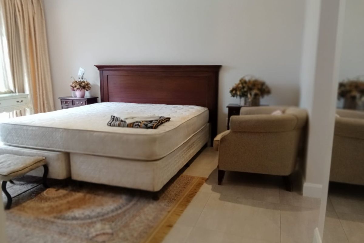A spacious bedroom featuring neutral tiled flooring and large windows with curtains, offering a clean and functional living space.