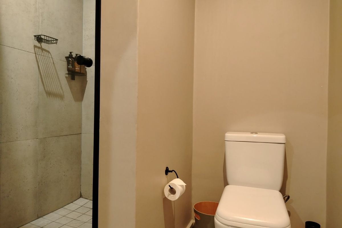 A functional bathroom featuring a modern toilet and a separate shower enclosure with neutral wall tiling.