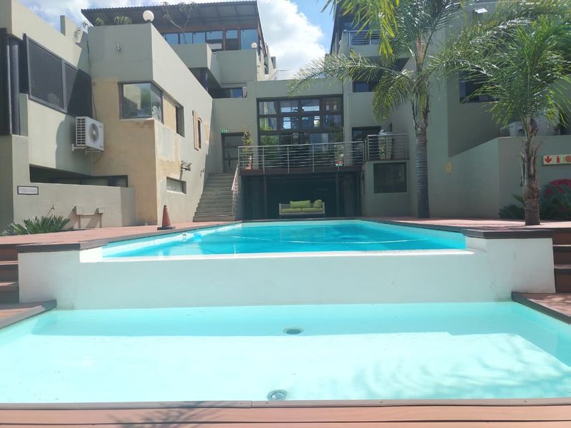 A multi-level outdoor pool area featuring tiered decking, a swimming pool, and access to the main building structure via an external staircase.