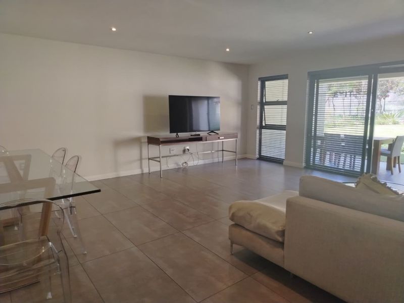 Spacious open-plan living and dining area featuring large format floor tiles, recessed lighting, and sliding glass doors providing access to the outdoor patio.