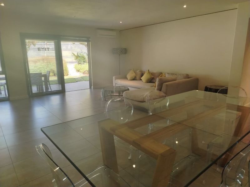 Spacious open-plan living and dining area featuring tiled flooring, recessed lighting, a wall-mounted air conditioner, and large sliding doors leading to the patio.