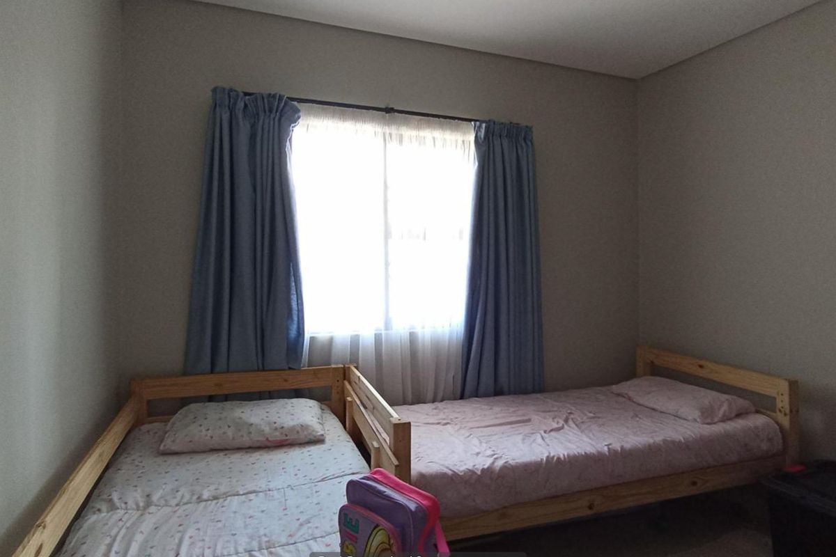 A standard bedroom featuring neutral wall tones and a window with curtains, providing a functional space for rest.