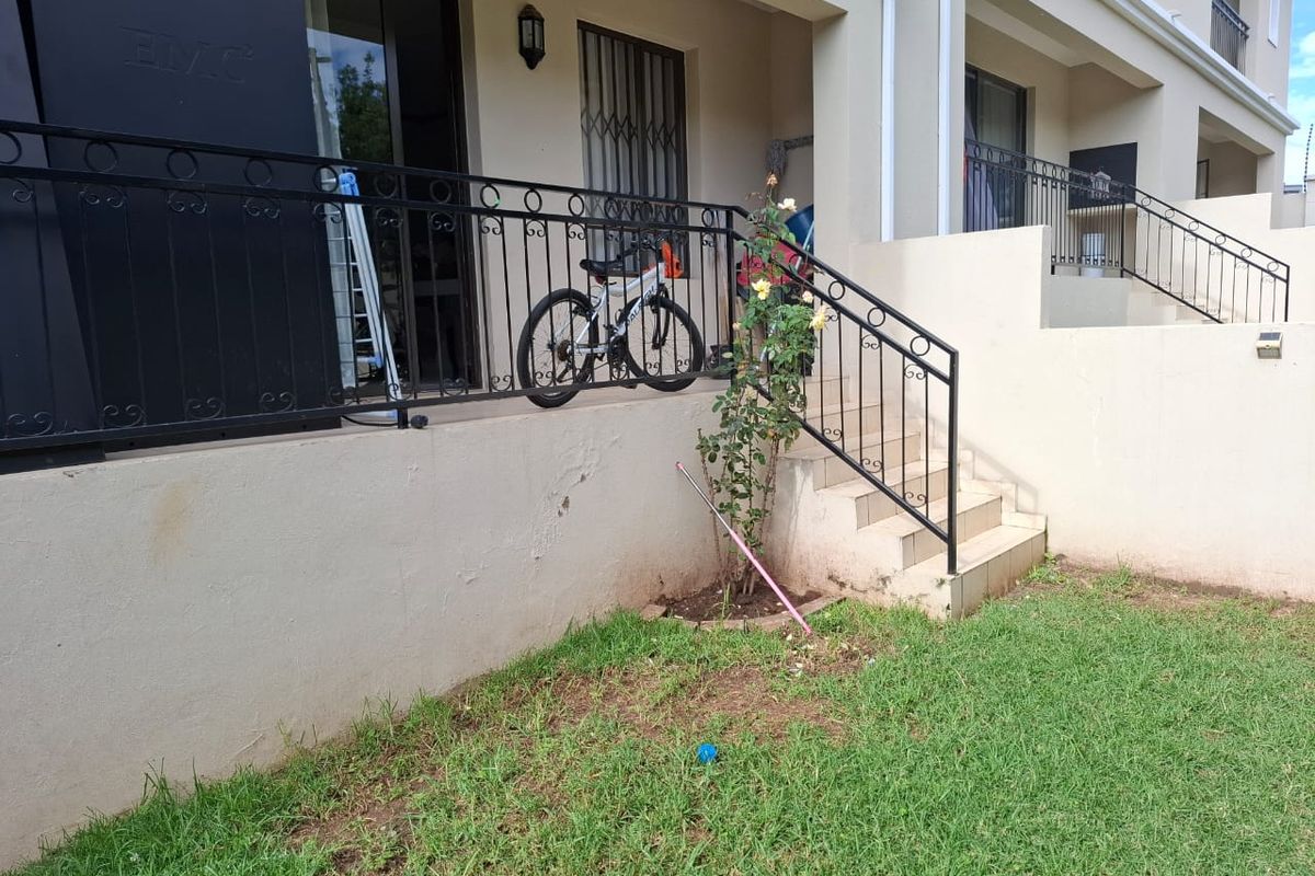 Rear exterior view of the townhouse featuring a raised patio area with wrought iron railings, tiled stairs, and access to the living space.