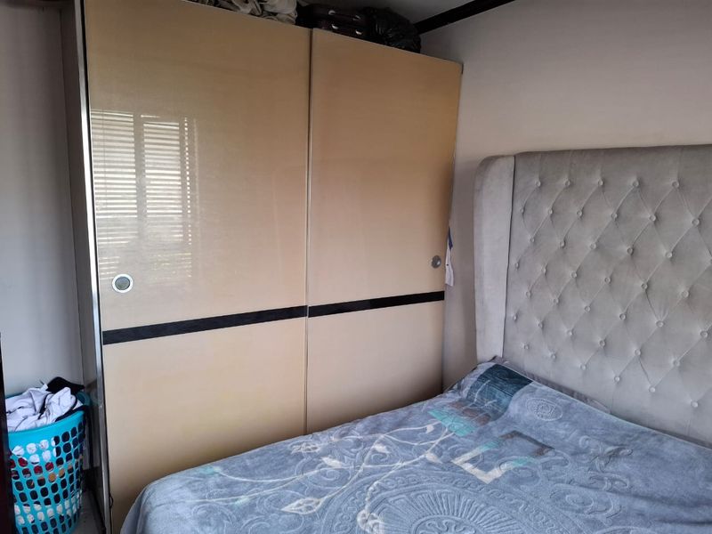 A bedroom featuring a large, modern built-in sliding door wardrobe with a neutral finish.