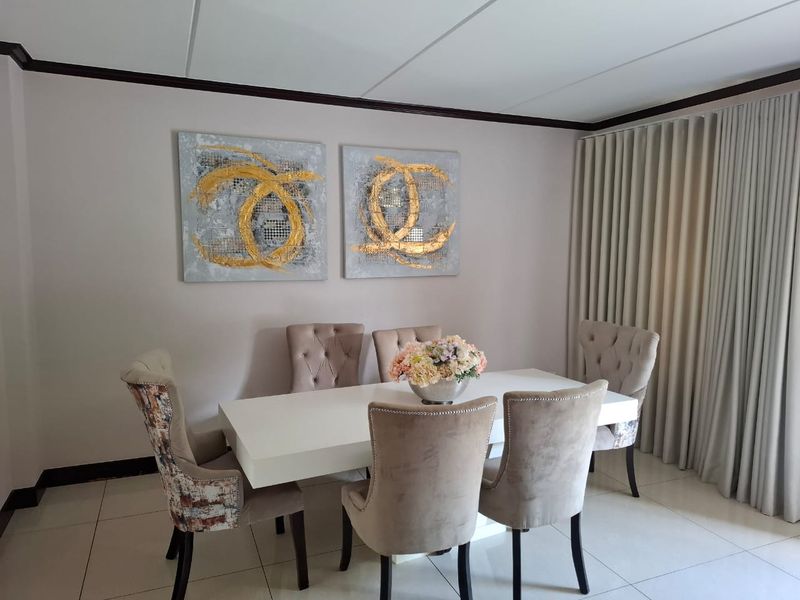A well-maintained dining room featuring neutral tiled flooring, a drop ceiling, and floor-to-ceiling curtains.
