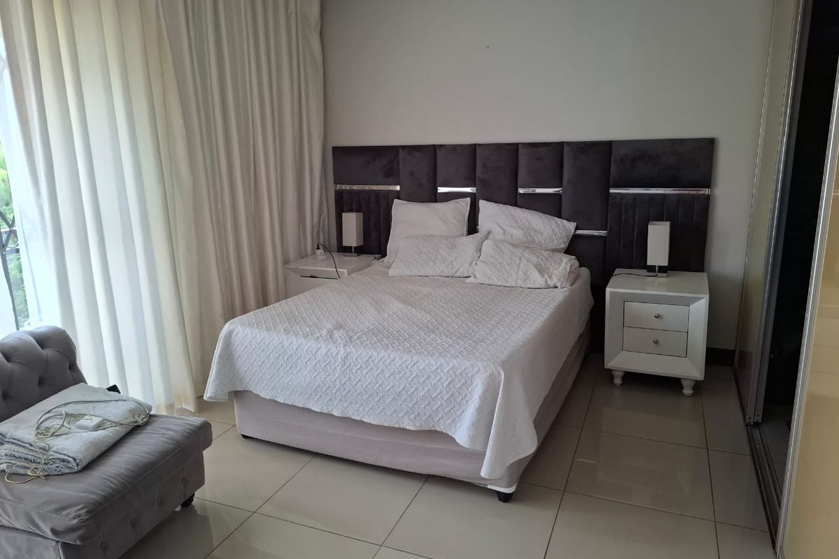 A well-maintained bedroom featuring tiled flooring, a built-in wardrobe, and direct access to an outdoor area through a sliding door.