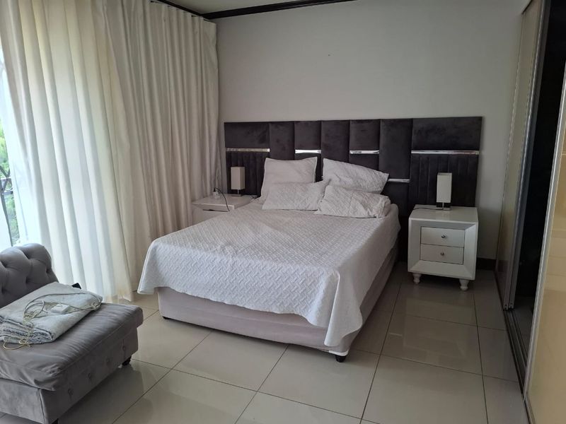 A well-maintained bedroom featuring tiled flooring, a built-in wardrobe, and direct access to an outdoor area through a sliding door.
