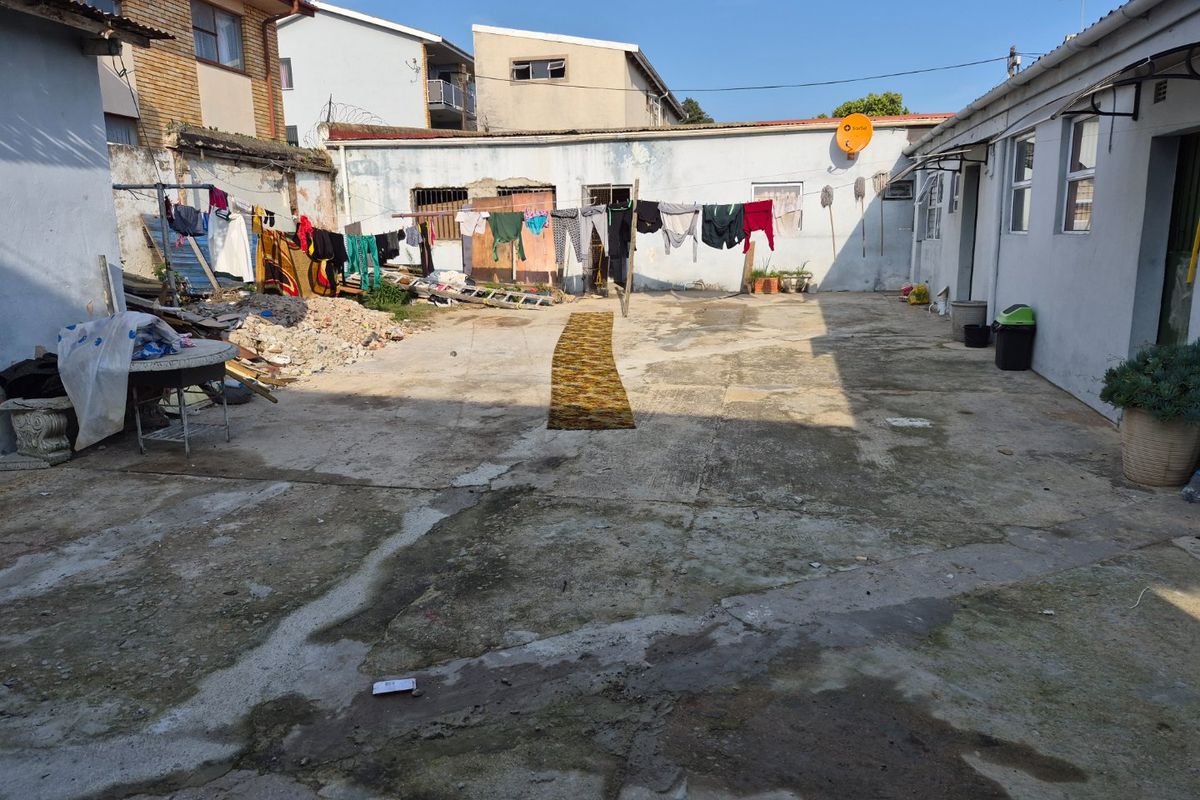 A spacious rear courtyard featuring concrete paving and boundary walls, requiring maintenance and landscaping to improve the overall exterior presentation.