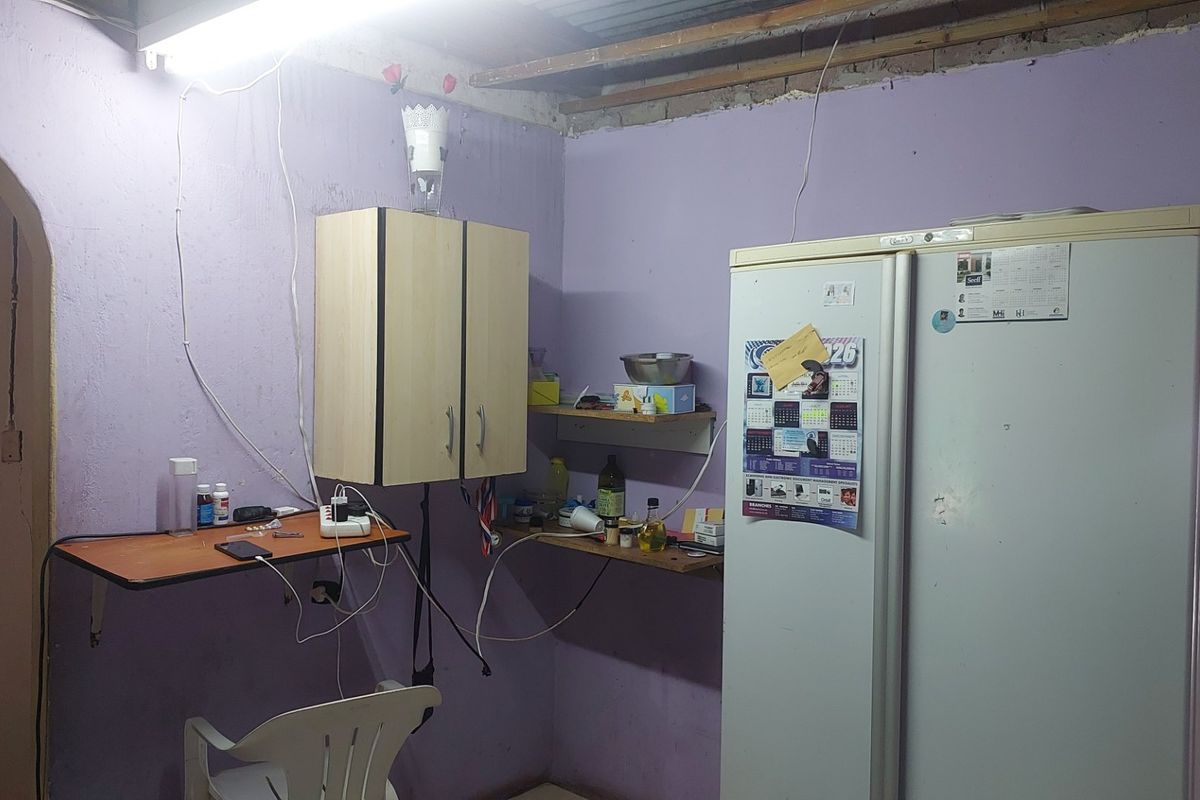 A basic kitchen area featuring wall-mounted cabinetry and exposed ceiling rafters, requiring significant cosmetic updates and finishing work.