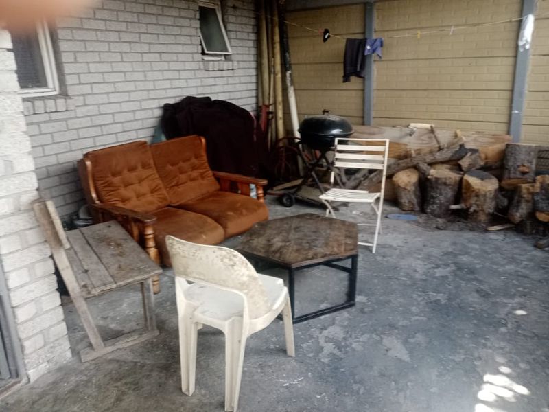 A covered outdoor patio area featuring brick walls and concrete flooring, suitable for renovation into a functional entertainment space.