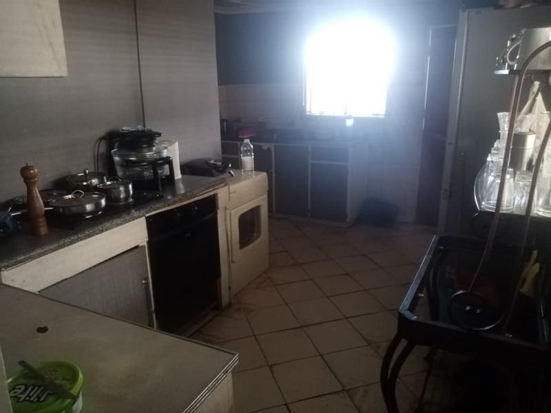 A dated kitchen featuring built-in cabinetry, an oven, and a hob, with tiled flooring and significant potential for modernization.