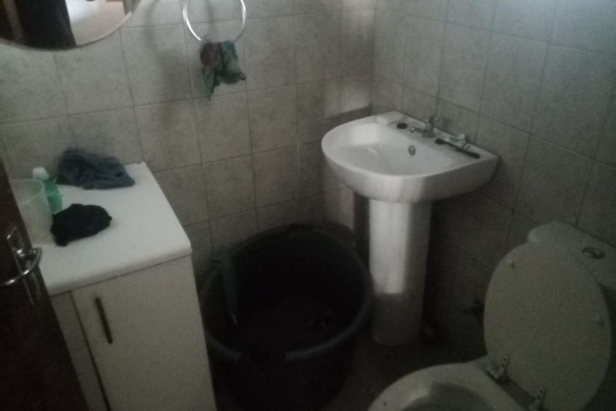 A compact bathroom featuring a pedestal basin, toilet, and vanity cabinet with tiled wall finishes.