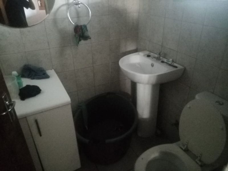 A compact bathroom featuring a pedestal basin, toilet, and vanity cabinet with tiled wall finishes.