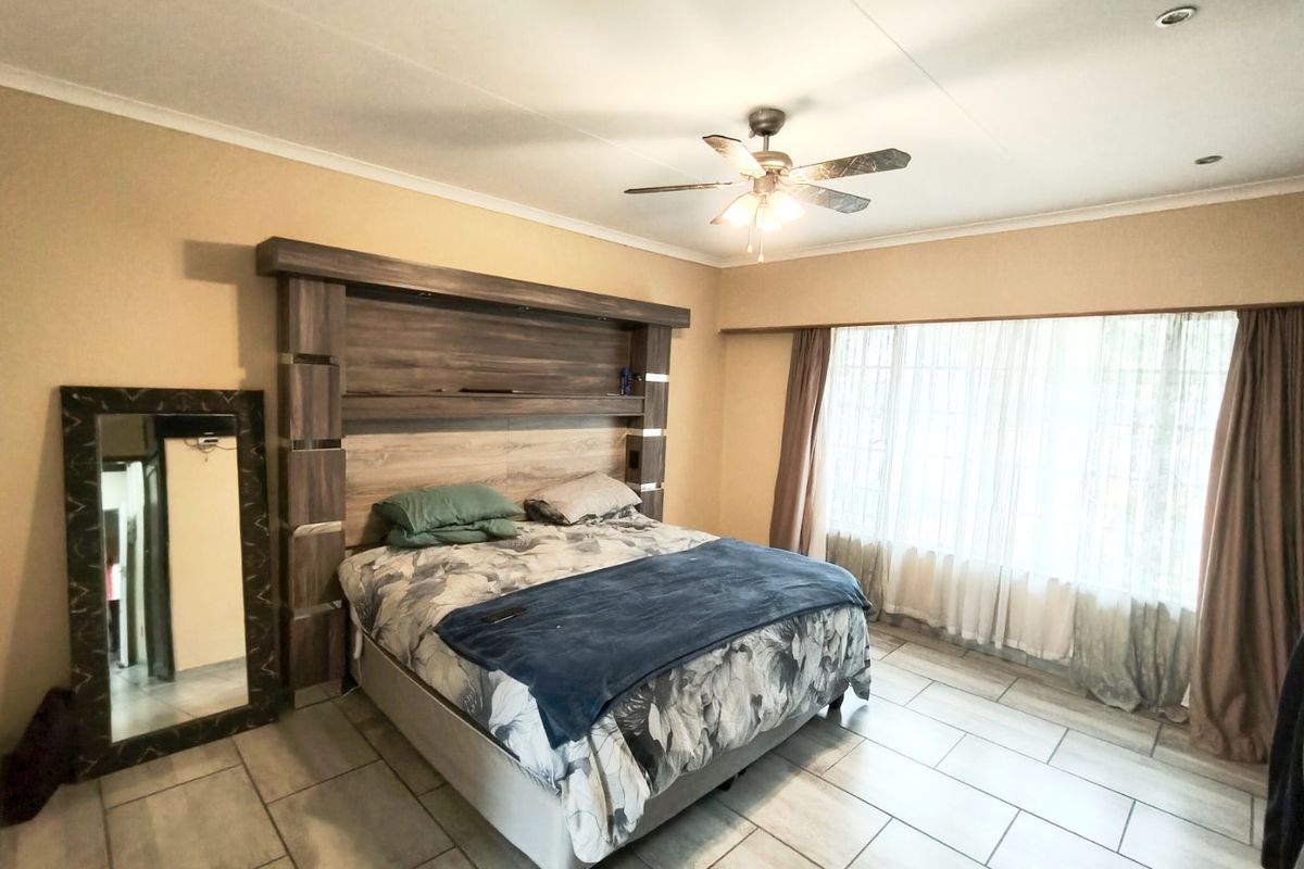 Spacious bedroom featuring tiled flooring, a ceiling fan, and a large built-in headboard unit with integrated shelving.