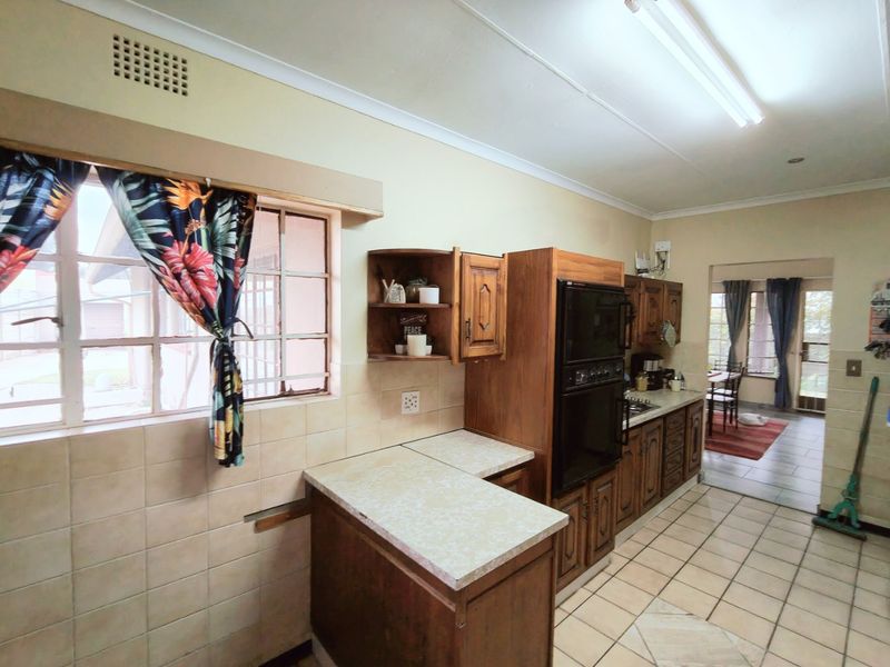 A dated kitchen featuring traditional wooden cabinetry, laminate countertops, and tiled flooring, offering significant potential for a modern renovation.