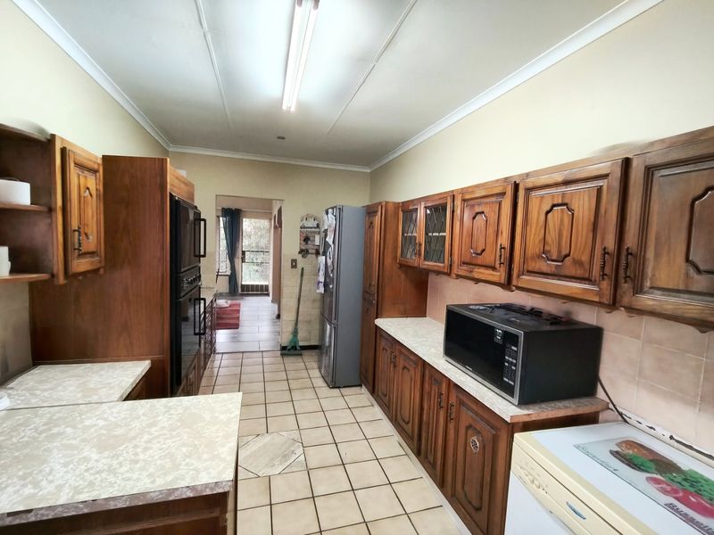 A functional kitchen featuring traditional wooden cabinetry, laminate countertops, and tiled flooring, offering potential for a modern renovation.
