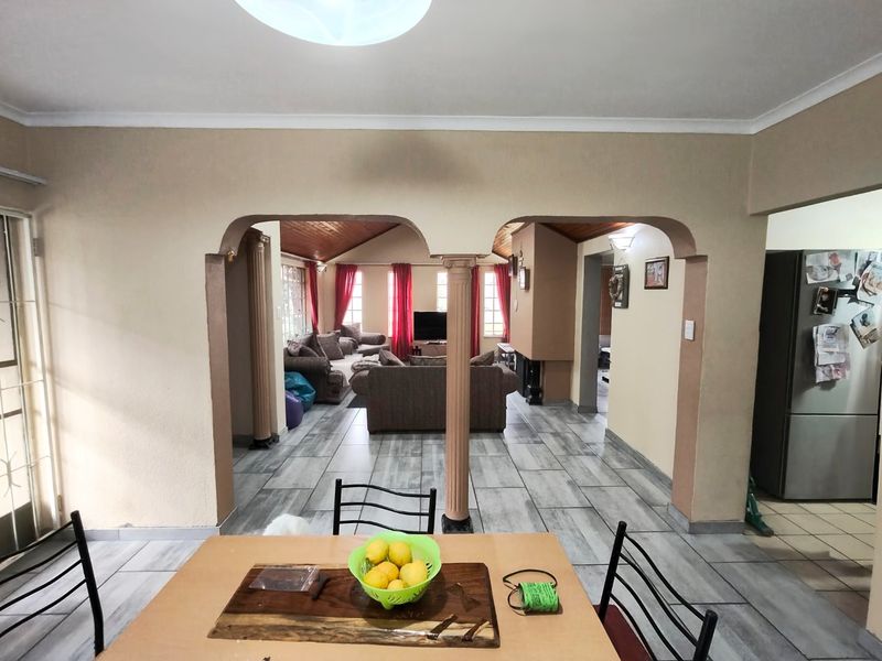 Open plan living area featuring tiled flooring, arched architectural dividers with decorative columns, and a vaulted ceiling, creating a connected and spacious layout.