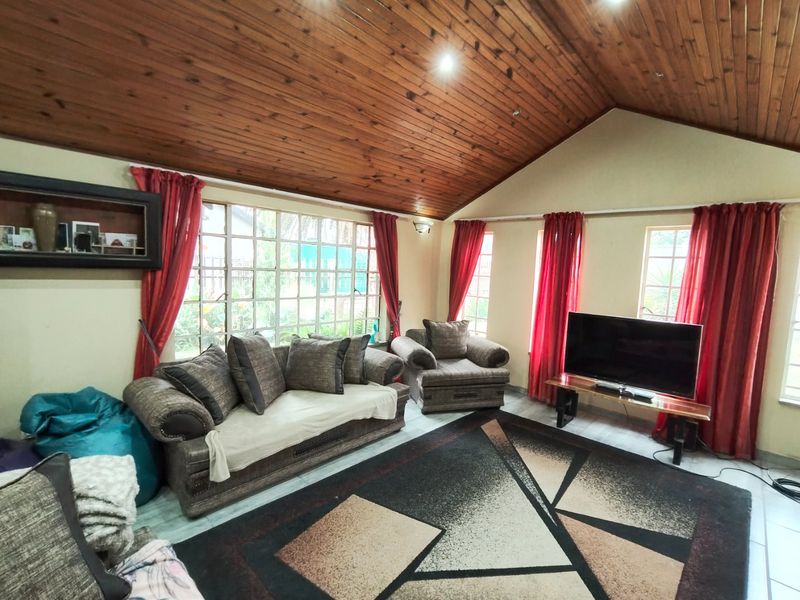 Spacious living room featuring a high vaulted timber ceiling, recessed lighting, and large windows that provide ample natural light.