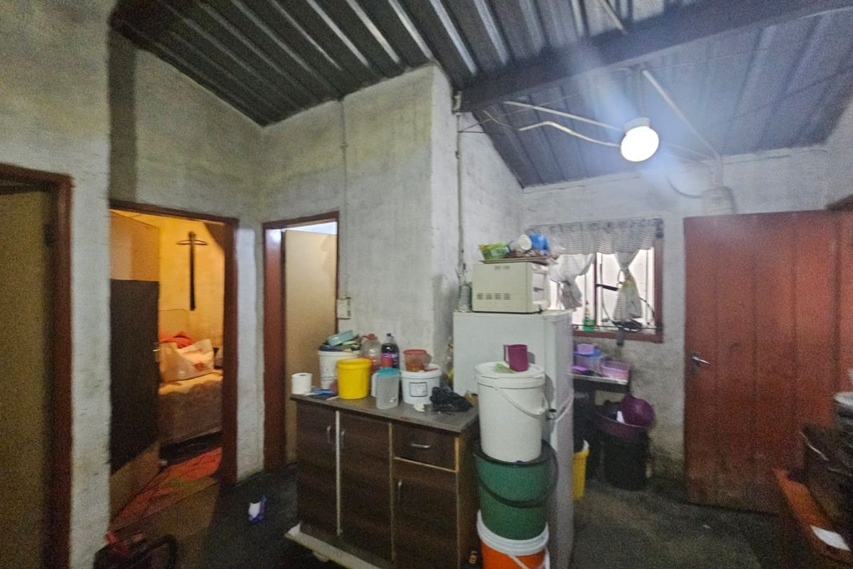 A basic kitchen area featuring exposed metal roofing and unfinished wall surfaces, requiring significant renovation to improve functionality and aesthetic appeal.