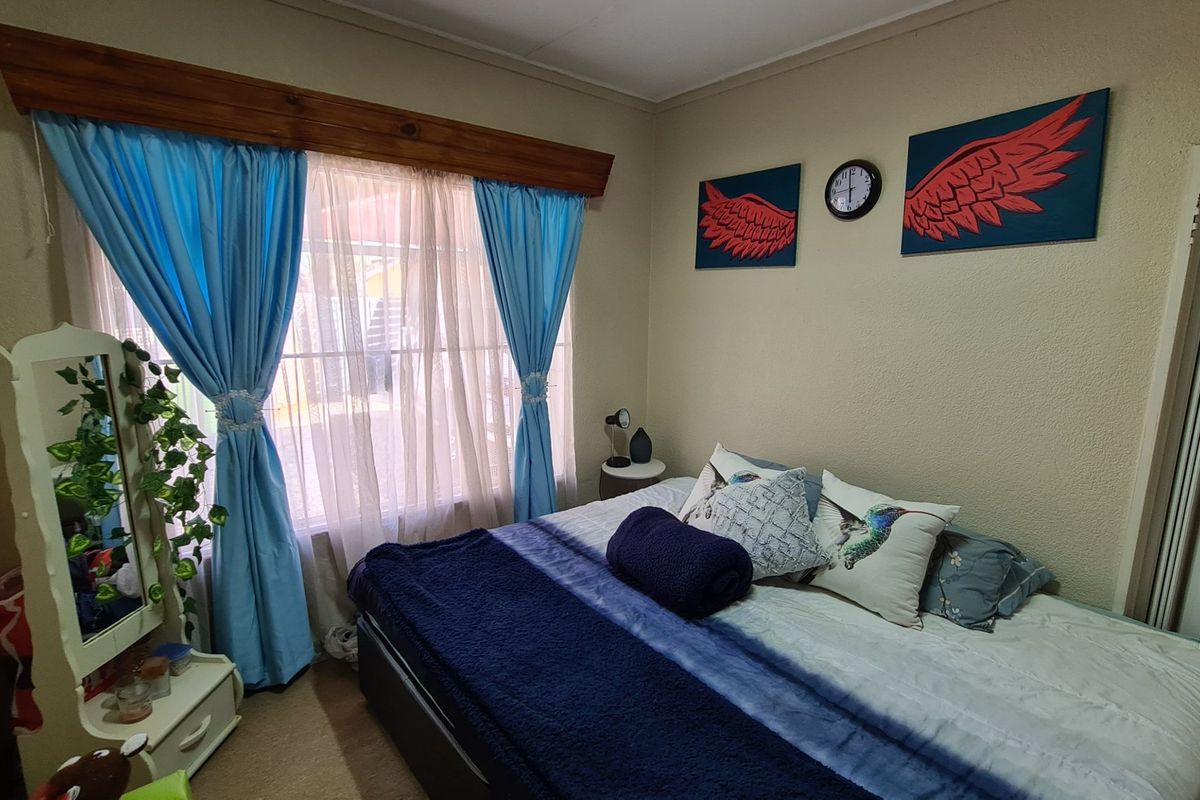 A standard bedroom featuring a built-in cupboard and a timber curtain pelmet above the window.