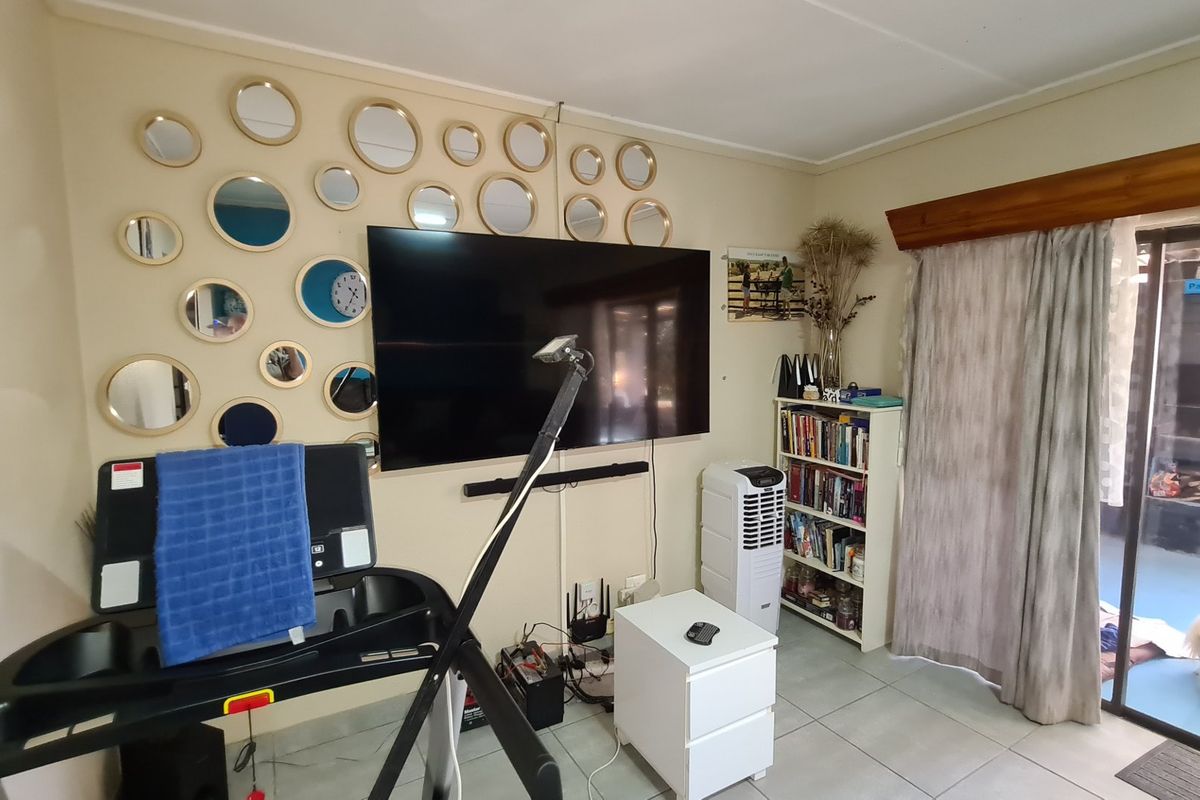 A living room area featuring tiled flooring and a large sliding glass door providing access to an outdoor space.
