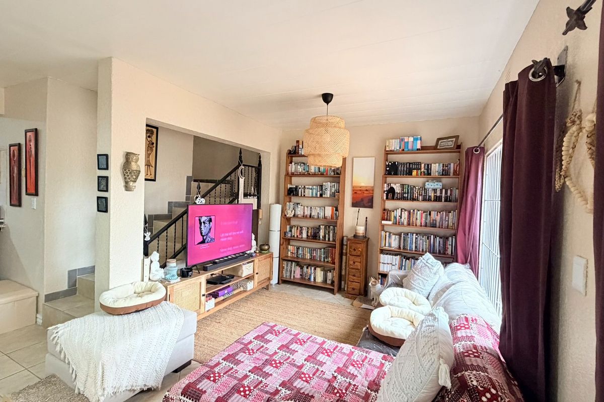 A comfortable living room featuring tiled flooring, a staircase, and a sliding glass door providing natural light.