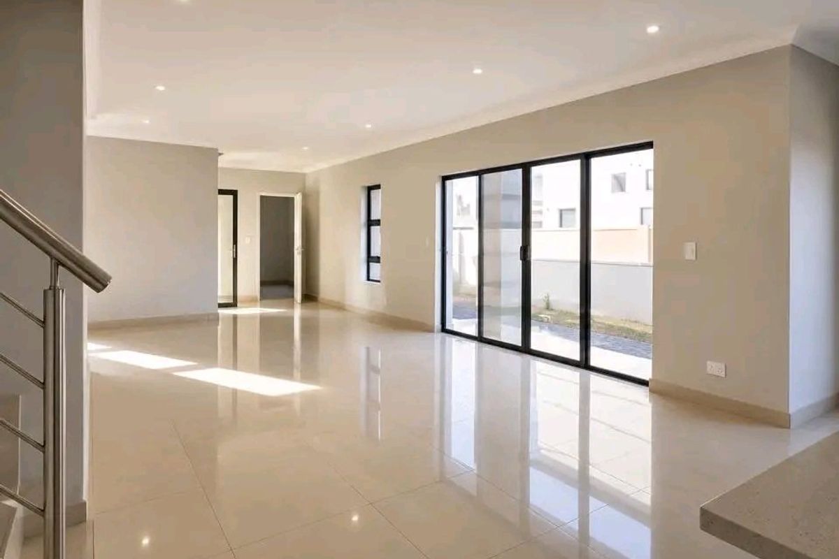 Spacious, modern open-plan living area featuring polished porcelain tiles, recessed lighting, and large aluminium sliding doors leading to the exterior.