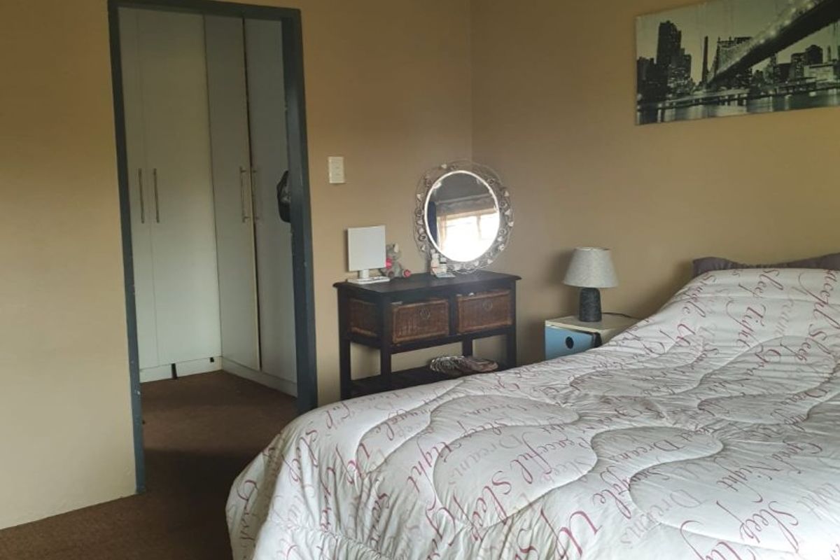 A bedroom featuring a ceiling fan and an adjoining walk-in closet area with built-in cupboards.